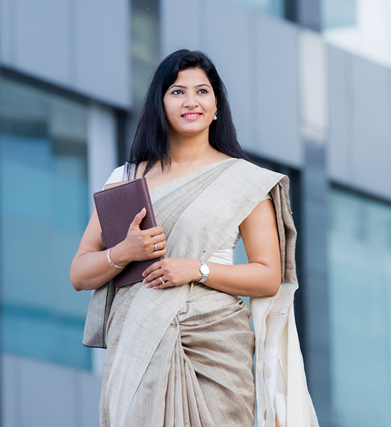 A portrait of a woman in a sari standing in front of an office building